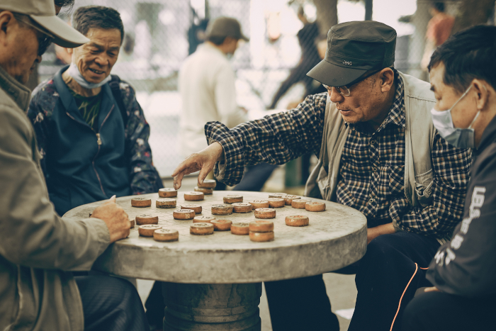 Hombres pekineses jugando al ajedrez chino en Beijing, China. Descubra la vida tradicional cotidiana de Beijing en bici