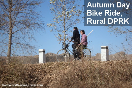 North Koreans ride a bike on an autumn day in the countryside