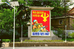 North Korean military propaganda poster outside the Minsok Folk Hotel in the old part of town of Kaesong city in North Korea, DPRK, with KTG Tours