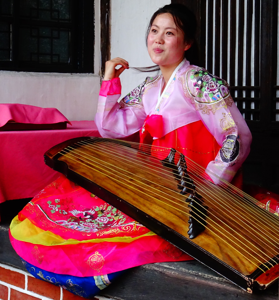 Chica de Corea del Norte tocando el instrumento tradicional coreano, el Kayagum, en el hotel tradicional folclórico de Kaesong en Corea del Norte. Tour organizado por KTG