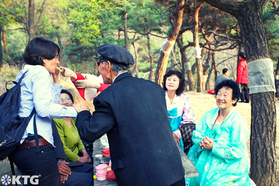 KTG western tourist in North Korea enjoying a picnic with North Koreans in Moranbong park ie Moran Hill in Pyongyang capital of North Korea on President Kim Il Sung's Birthday, one of the most important holidays in the DPRK.