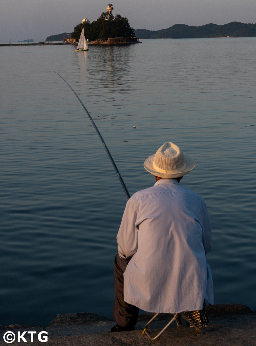 Man fishing in Wonsan city, Kangwon province, North Korea (DPRK). You can see the Jangdok islet in the background. Trip arranged by KTG Tours