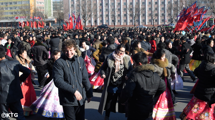 Un membre du personnel de KTG dansant avec des Coréens lors de danses de masse à l'occasion de l'anniversaire du leader Kim Jong Il à Pyongyang, Corée du Nord (RPDC)