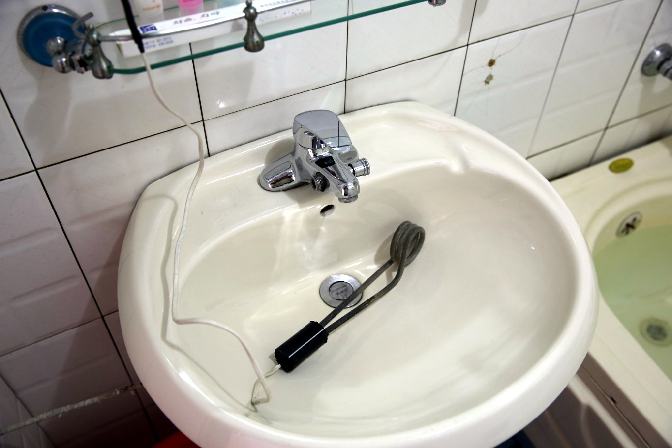 Sink at a toilet in a villa in the Majon bathing resort, North Korea. Notice the electric rods used to heat the water