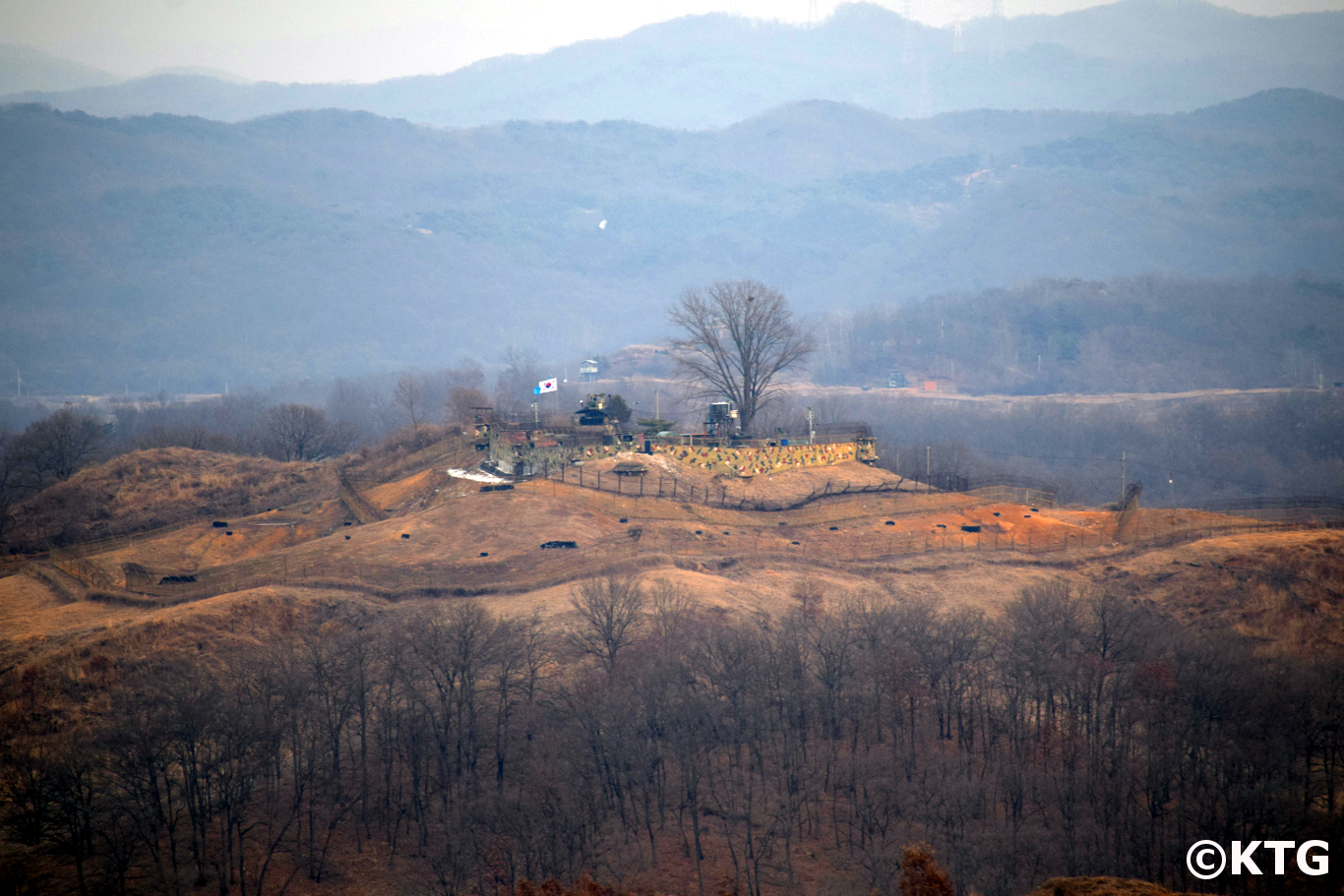 South Korean military post across the DMZ seen from North Korea. You can see the UN and South Korean flags fluttering in the wind. Trip arranged by KTG to see the Concrete Wall from Kaesong in North Korea