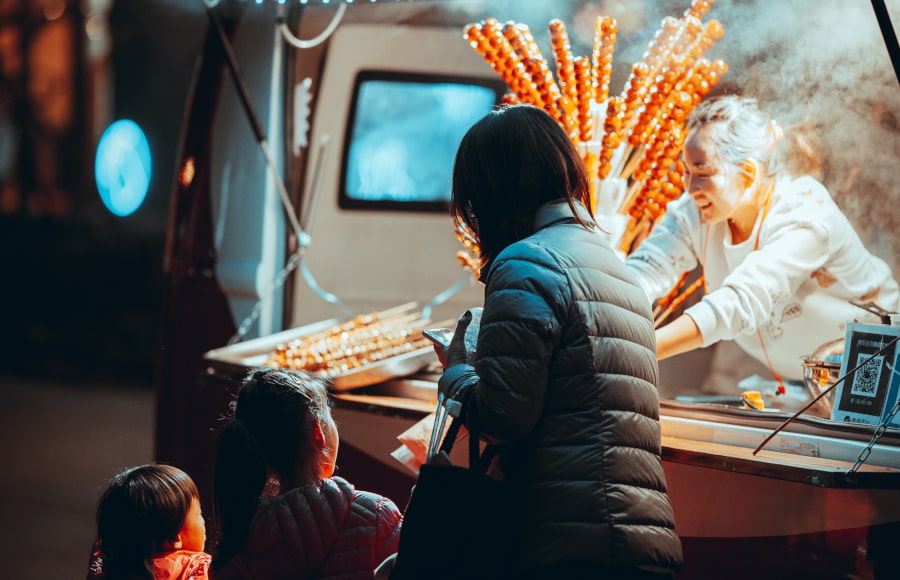 Familia comprando tanghulu en los hutongs de Beijing, Pekin, China