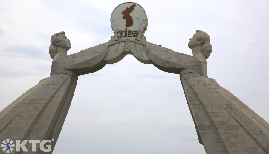 Monumento de granito de dos damas coreanas vestidas con trajes tradicionales coreanos sosteniendo el estandarte de las Tres Cartas para la Reunificación de Corea. El Arco de la Reunificación se encuentra en las afueras de Pyongyang, capital de Corea del Norte, RPDC. Viaje organizado por KTG Tours