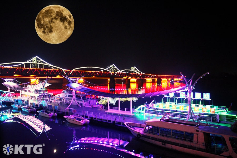 Puente roto brillantemente iluminado por la noche en la ciudad de Dandong, provincia de Liaoning en China, ciudad fronteriza con Corea del Norte (RPDC). Tour organizado por KTG Tours