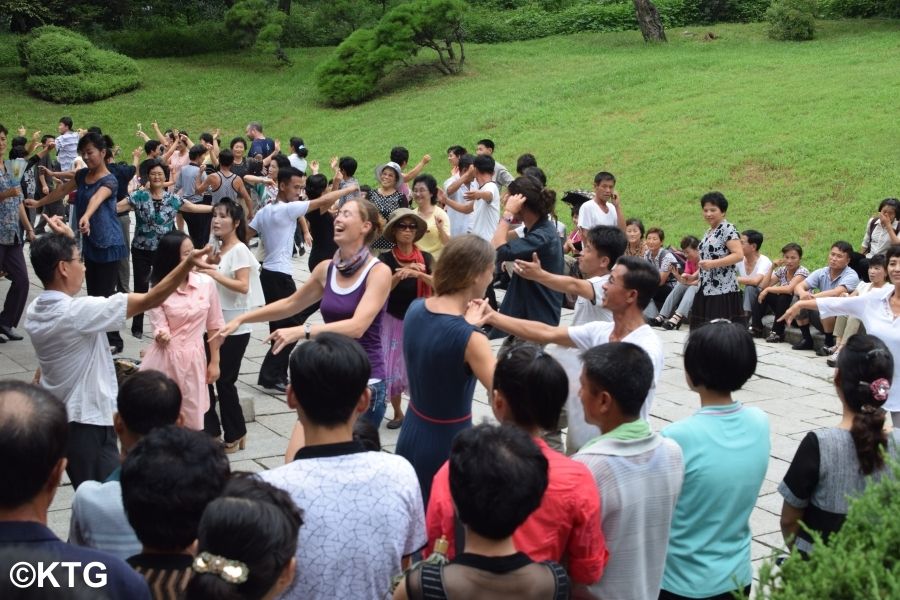 Viajeros de KTG bailando con norcoreanos en el Parque Moran en Pyongyang, Corea del Norte, en el Día de la Liberación