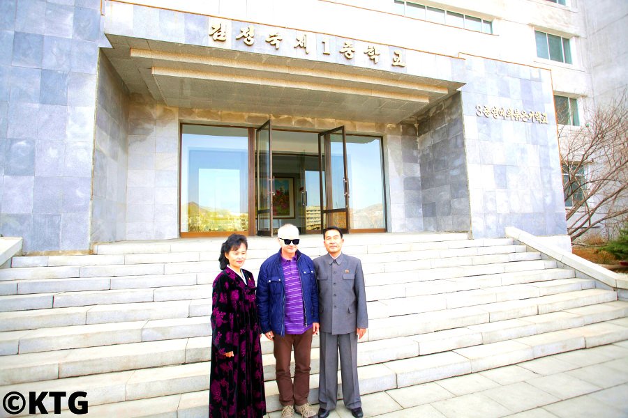 Viajero de KTG Tours en la escuela secundaria número uno Kim Jong Suk en la ciudad de Pyongsong, capital de la provincia de Pyongan del Sur con el director de la escuela y un maestro
