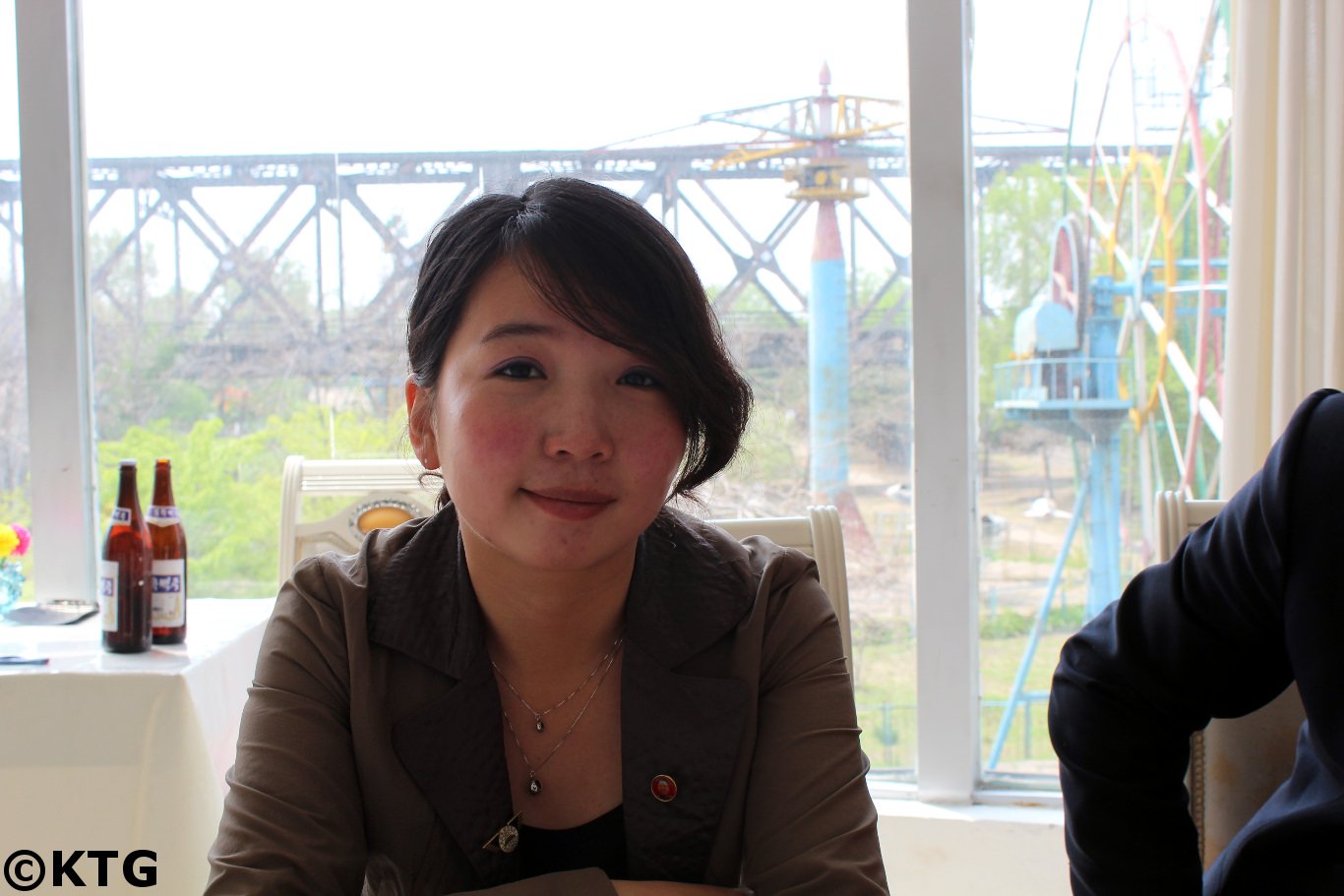 Ms Kim, North Korean guide from Pyongyang having lunch at the Myohyansgan agency restaurant in Sinuiju city in North Korea, DPRK, just across from Dandong in China. The bridge in the background is the friendhsip bridge that connects both countries. Picture taken by KTG Tours