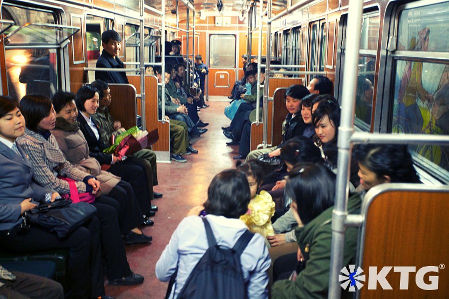 locals smile at the Pyongyang metro in North Korea as a western KTG traveller shows a Korean girl a picture she just took, North Korea, DPRK