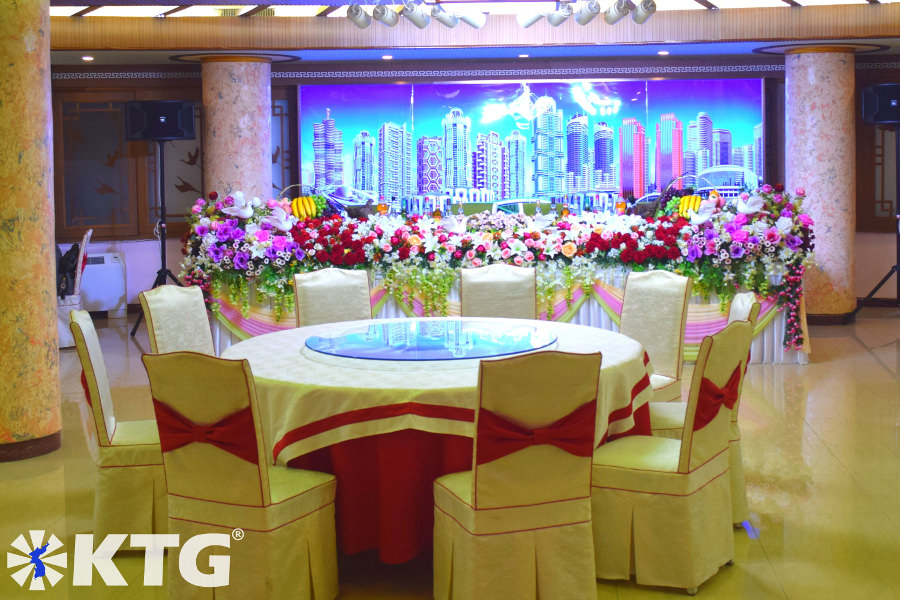 Table dressée pour un banquet de mariage nord-coréen. Vous pouvez voir la nouvelle ligne d'horizon de Pyongyang dans l'image d'arrière-plan; Mirae Future Scientists Street, Ryomyong Street et Changjon Street. Ce restaurant dans le bâtiment Lotus sur la rue Romyong à Pyongyang. Découvrez avec KTG Tours!