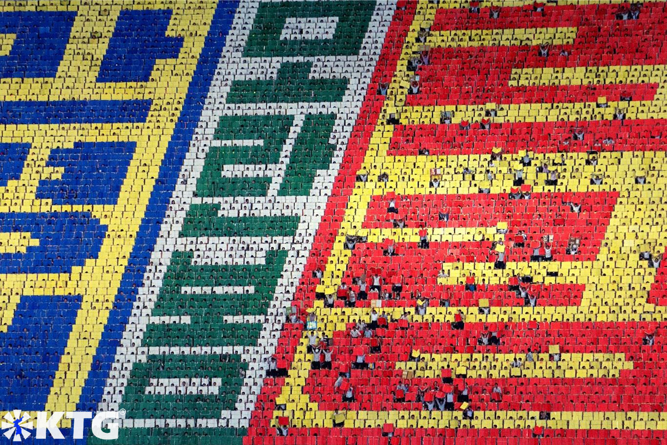 North Korean students form a giant human mosaic at the Mass Games in Pyongyang, North Korea (DPRK). Each student hold a book and forms a tiny pixel consisting of over 17 thousand people. Photo in North Korea taken by KTG Tours