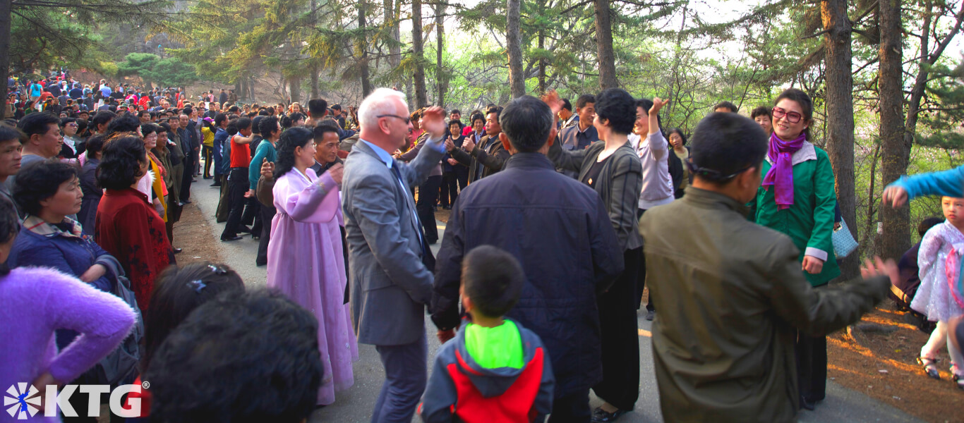 North Koreans dancing with a foreigner in Moranbong Park ie Moran Hill. This western traveller went to Pyongyang with KTG tours. Moran Hill is full of thousands of North Koreans on major DPRK holidays.