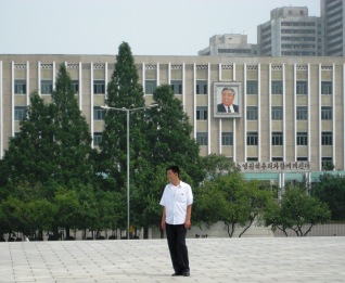 joven en corea del norte con el retrato de Kim Il Sung en el fondo
