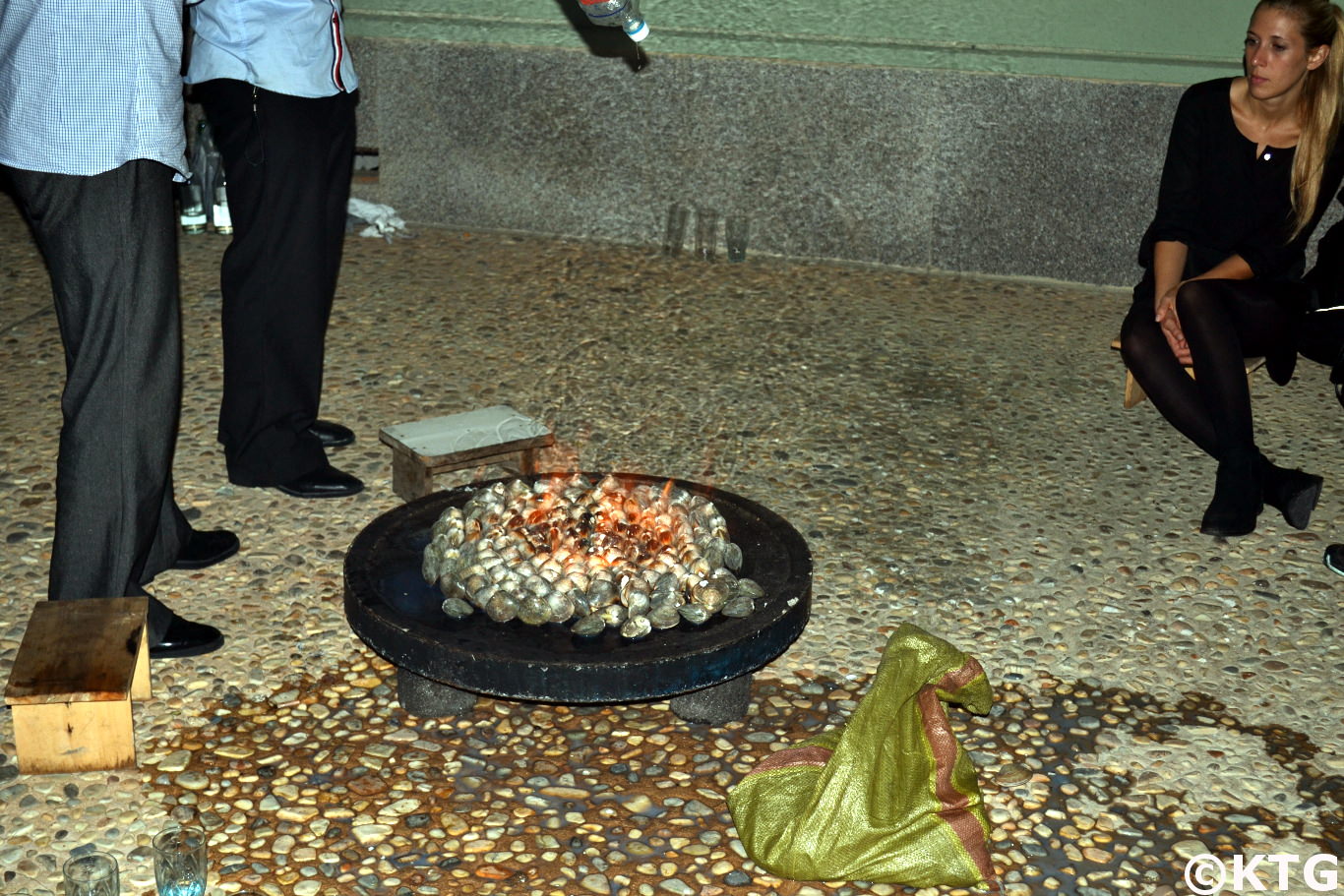 Viajera de KTG observa cómo nuestro conductor vierte gasolina sobre almejas en el Nampo Ryonggang Hot Spa Hotel en el condado de Onchon, cerca de la ciudad de Nampo, Corea del Norte (RPDC)