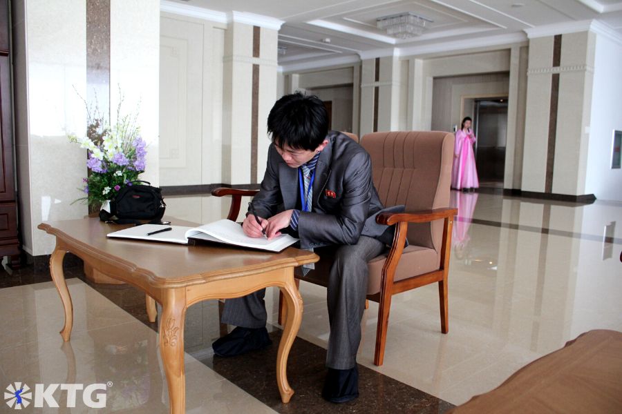 North Korean guide and friend, Mr. Pak, translating our traveller's impressions into Korean at the National GIfts Exhibition Centre in the outskirts of Pyongyang, DPRK