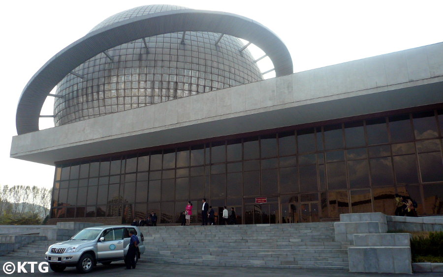 Coche en Corea del Norte junto a la Sala de Exposición de las Tres Revoluciones en Pyongyang