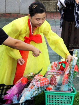 Mujer norcoreana posando flores para al pie de una estatua de Kim Il Sung