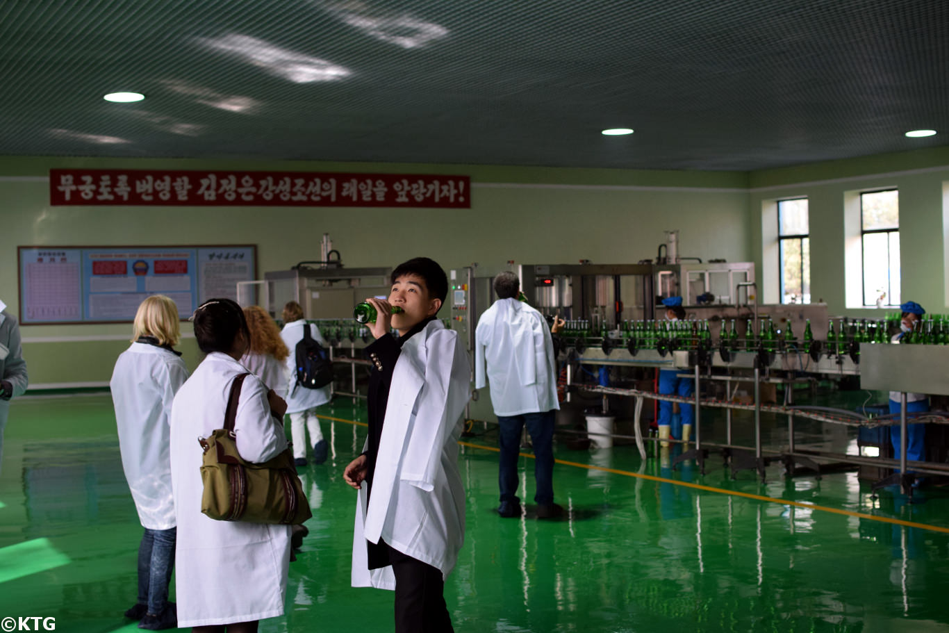 North Korean university student drinking water at the Kangso mineral water bottling factory near Nampo city, North Korea (DPRK). Trip arranged by KTG Tours