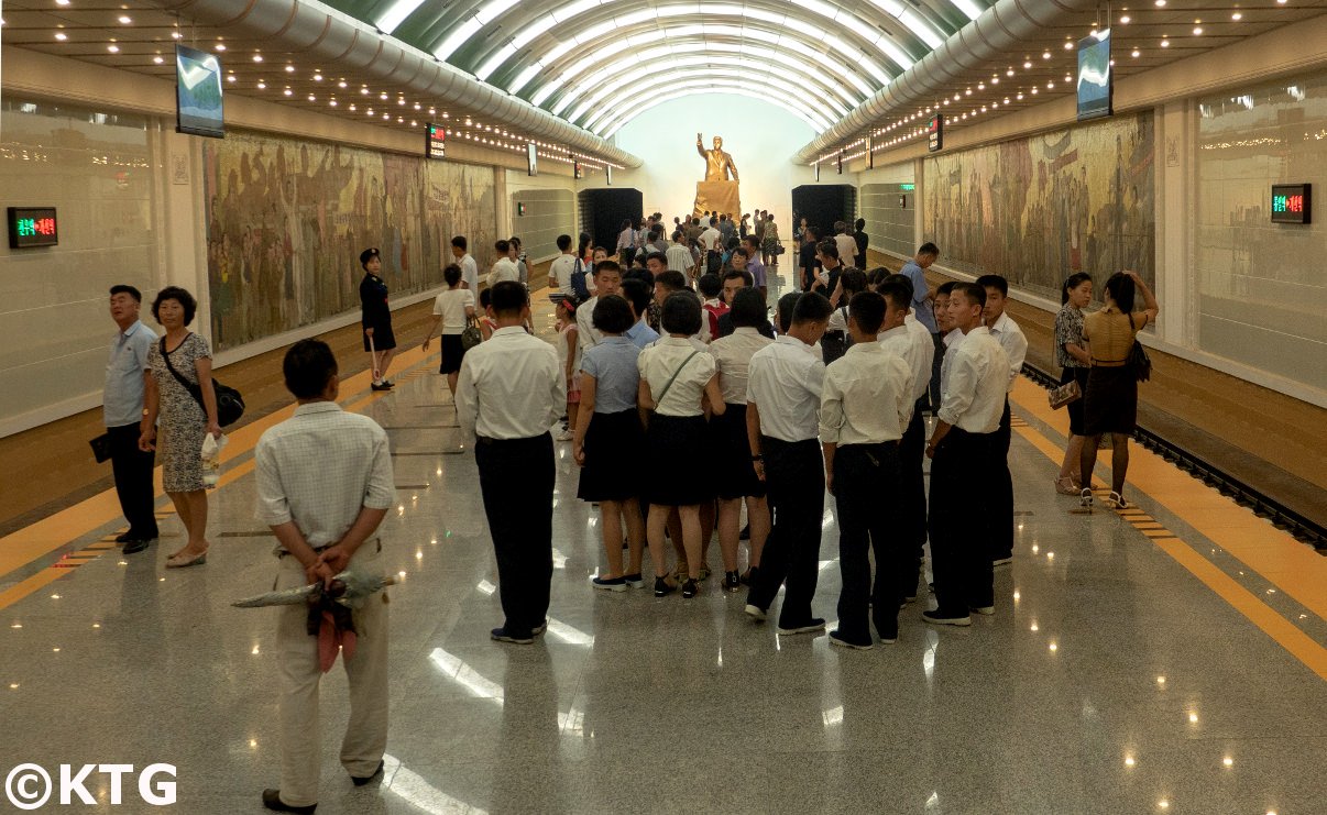 North Korean students on the platform at Kaesong station. This Pyongyang metro station has a bronze bust of President Kim Il Sung showing his triumphal speech after the Liberation of Korea from Japan in 1945. Picture of North Korea taken by KTG Tours