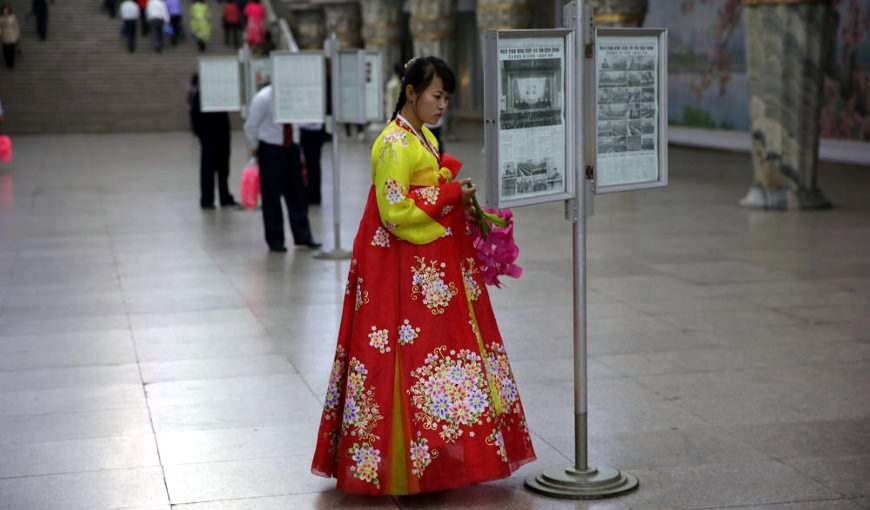 Dame nord-coréenne portant une robe traditionnelle coréenne en lisant le journal au métro de Pyongyang