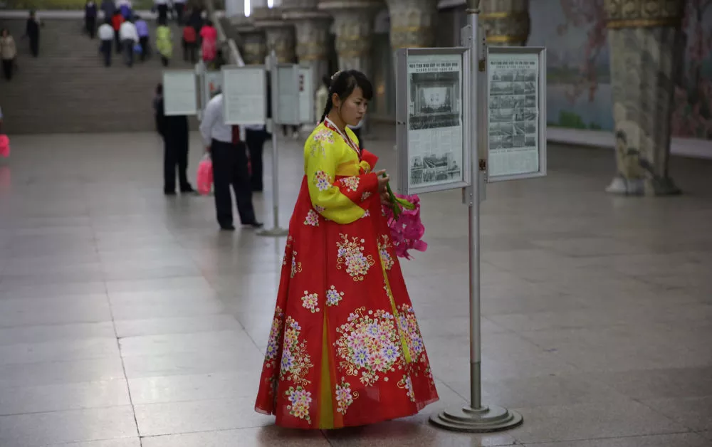 North Korean lady reading a framed newspaper in the Pyongang metro, DPRK