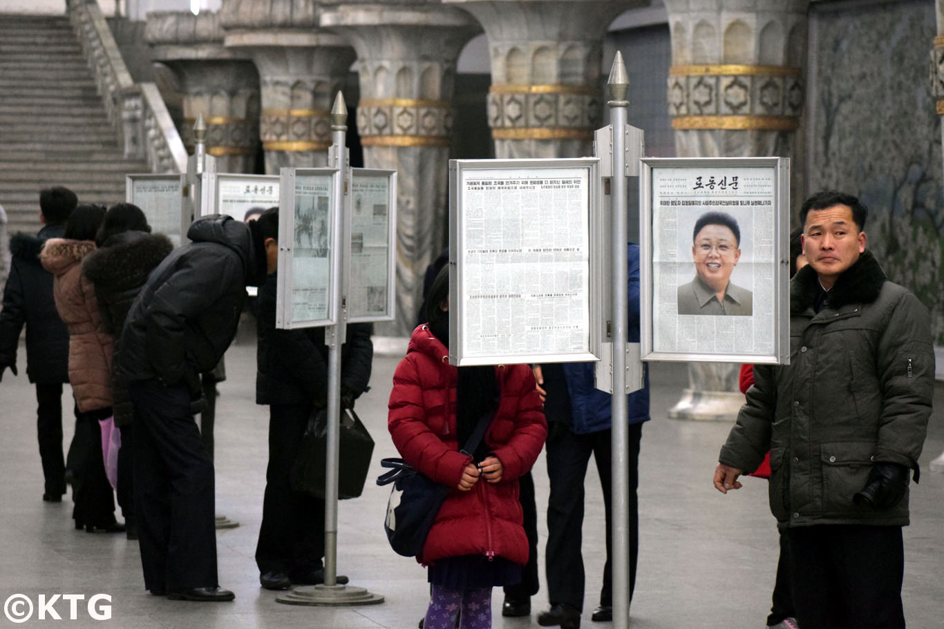 North Koreans reading newspaper at the Pyongyang metro