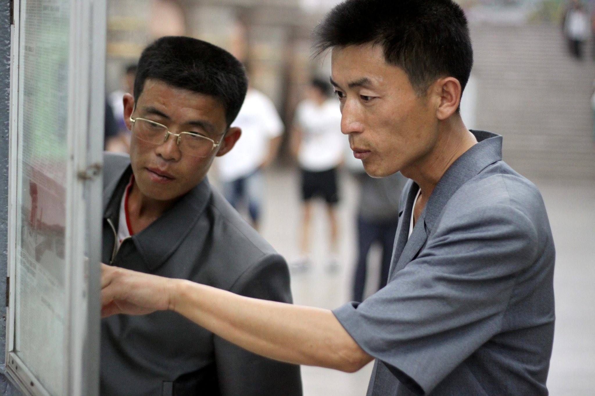 North Koreans reading newspaper at the Pyongyang metro