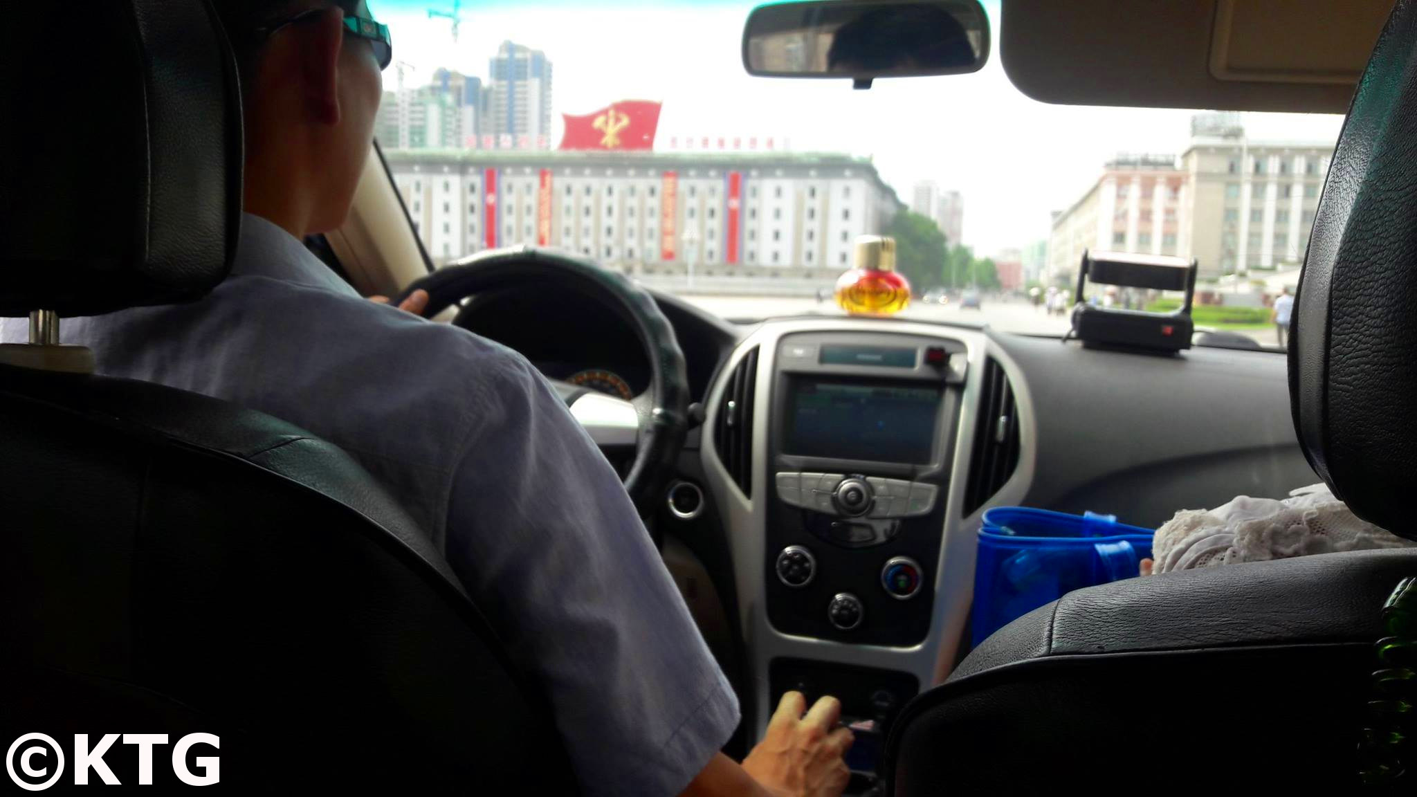 Taking an Air Koryo taxi through Kim Il Sung square in Pyongyang capital city of North Korea, DPRK, with KTG Tours